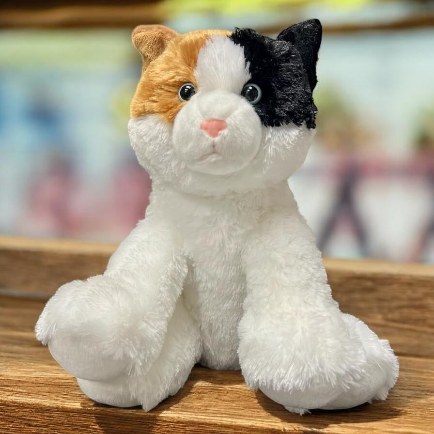 Photo of a large calico cat plush on a colorful background.