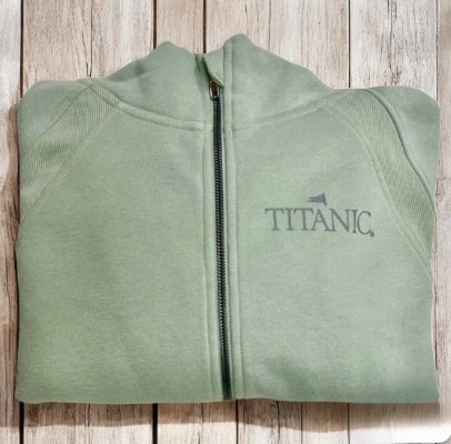 A sage green hoodie, folded, with a dark sage Titanic logo printed on one side of the chest.