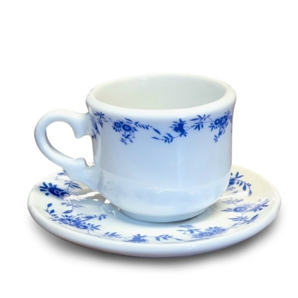 A mini teacup with navy blue floral trim sitting on a matching saucer. The teacup is a little smaller than a shot glass.