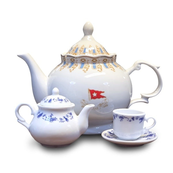 The mini second class teapot and teacup with saucer next to a full sized first class teapot for scale. The mini is about half the height of the full size teapot.