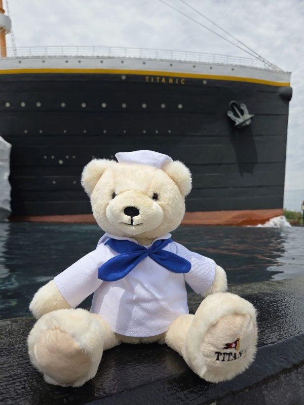 Polar bear plush in sailor shirt and hat next to Titanic ship.