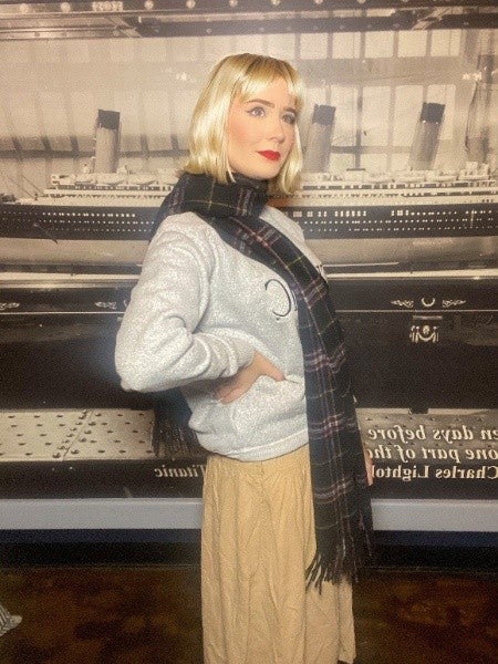 A warmly dressed woman wears her black tartan stole wrapped around her neck like a thick scarf.