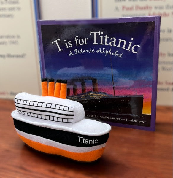 A small plush Titanic toy made of white, black, and orange fabric next to the storybook "T is for Titanic: A Titanic Alphabet".