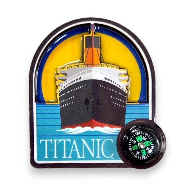 An arch shaped magnet showing Titanic from straight on the front of the bow. There is a small working compass in one corner. The ship is illustrated in bold colors set in front of a bright yellow moon.