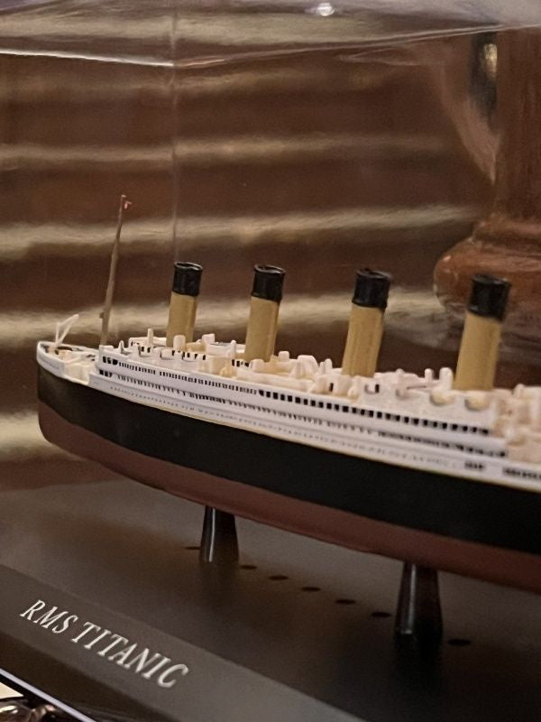 A closeup of the diecast titanic model in its acrylic dust cover. The windows along the sides can be seen, and there are many 3D details along the deck.