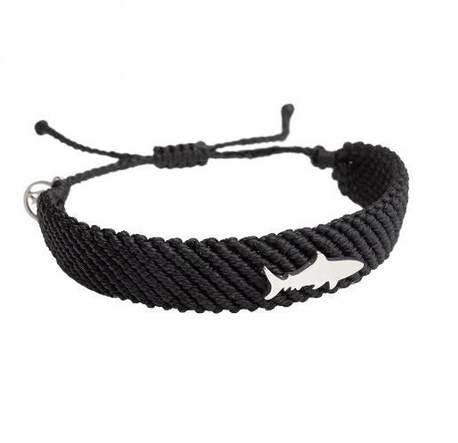A bracelet made of solid black braiding and accented with a silver-tone metal shark charm.