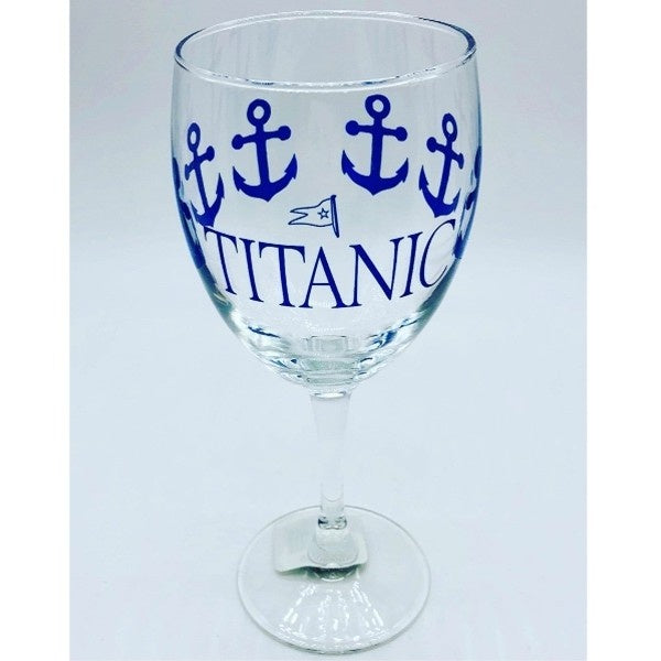 A clear wine glass printed with navy blue anchors wrapping around the glass, and our Titanic logo printed largely on one side.