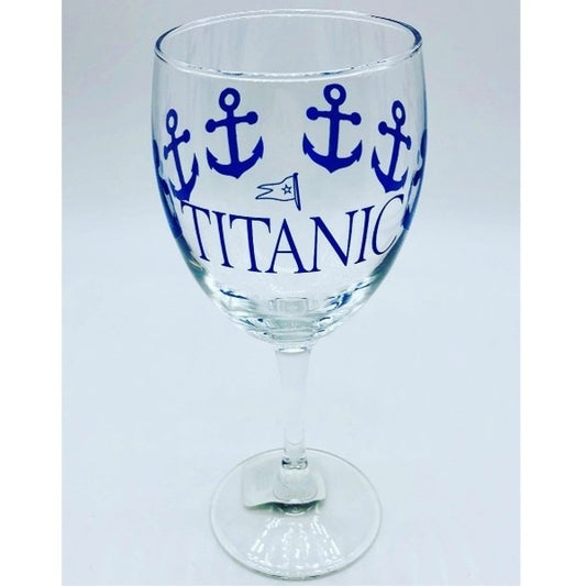 A clear wine glass printed with navy blue anchors wrapping around the glass, and our Titanic logo printed largely on one side.