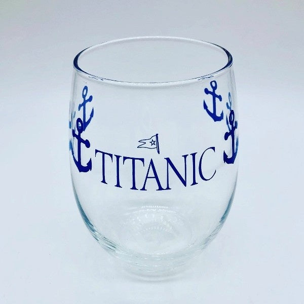 A clear stemless wine goblet printed with navy blue anchors wrapping around the glass and our Titanic logo printed largely on one side.