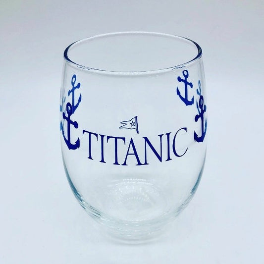 A clear stemless wine goblet printed with navy blue anchors wrapping around the glass and our Titanic logo printed largely on one side.