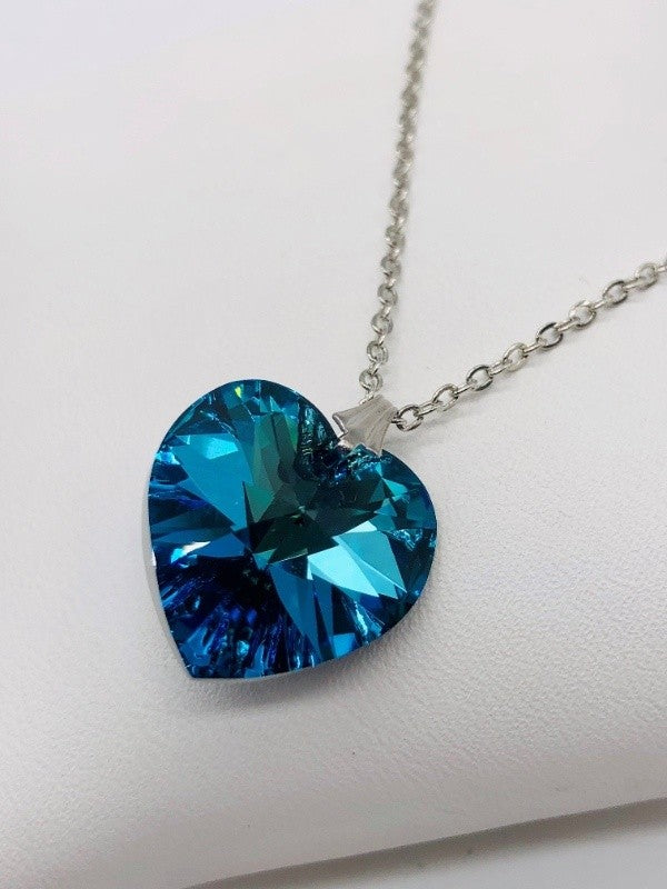 Zoom of light blue heart gem with many facets reflecting light.