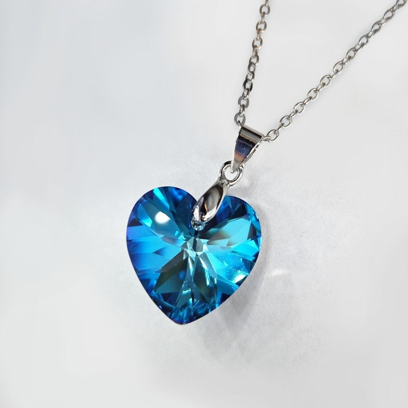 Bright light blue gemstone heart hanging from sleek silvery hardware.