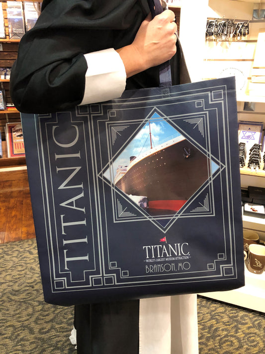 Navy blue large reusable tote bag with gray art deco detail and photo of Titanic Museum Attraction modeled by a First Class Maid.
