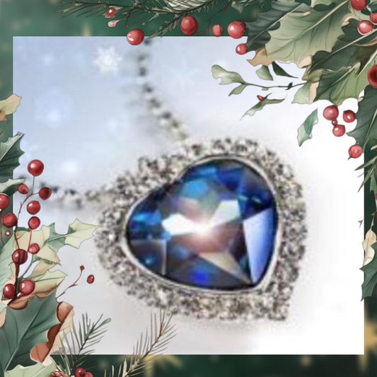 A large blue heart pendant shines under a light, festive green leaves and red berries frame the image.