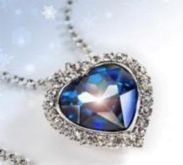 A large blue gem heart necklace set in a border of clear stones on a gemstone chain.