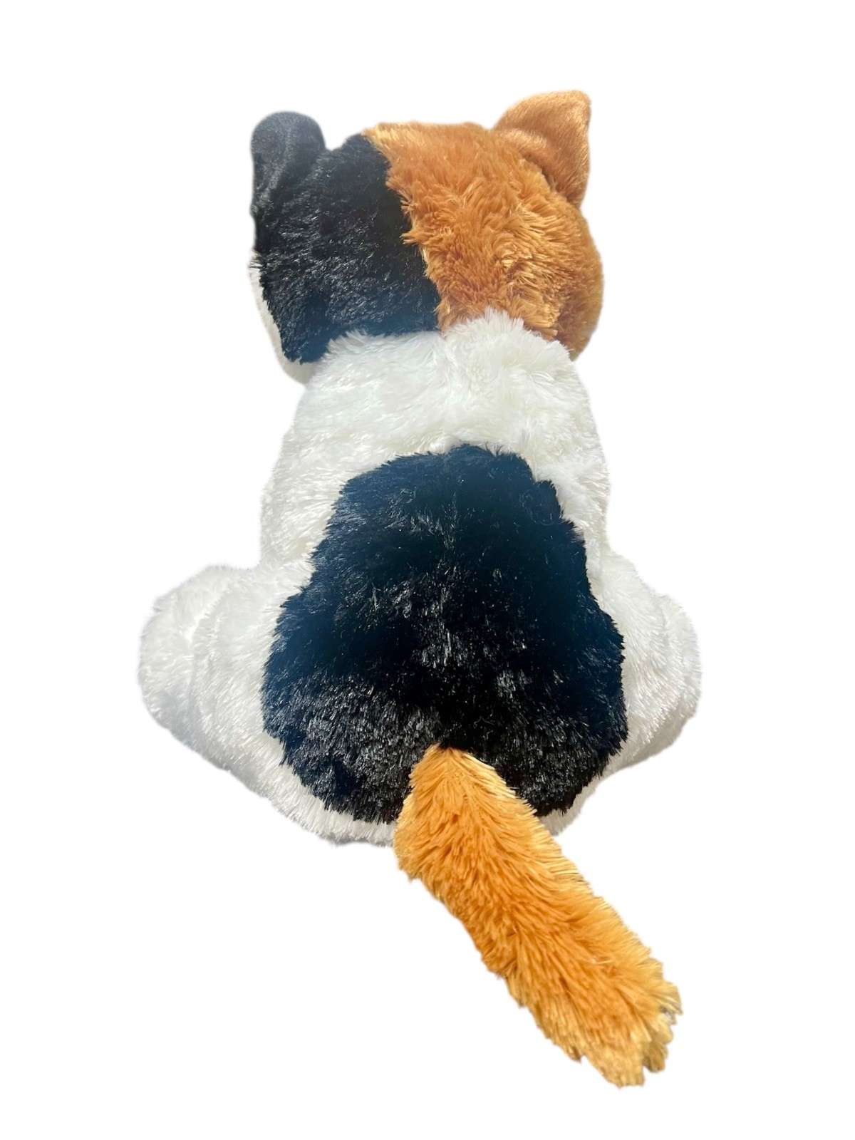Back of the calico cat plush, it has a black spot on its back and a brown tail.