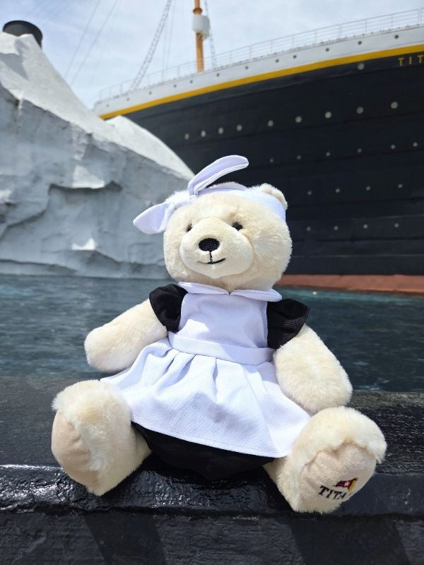 Polar bear plush wearing vintage black and white maid dress next to Titanic ship.