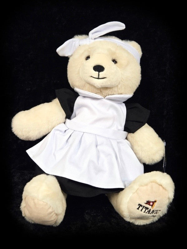 Polar bear plush wearing black dress with white apron and bow like a Titanic maid.
