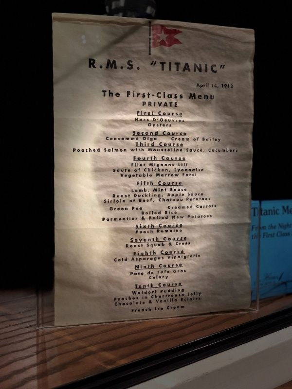 A full view of the replica 1st class menu with all ten courses beginning with hors d'oeuvres and oysters and ending with desert options including Peaches in Chartreuse Jelly, Eclairs, or French Ice Cream.