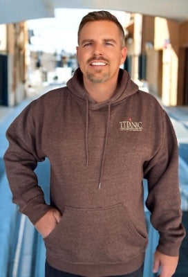 A man poses while wearing a brown hoodie with a small Titanic logo on the chest.