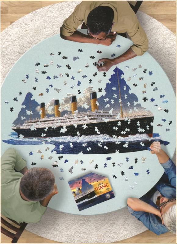 Three people around a table putting together the Titanic-shaped puzzle.