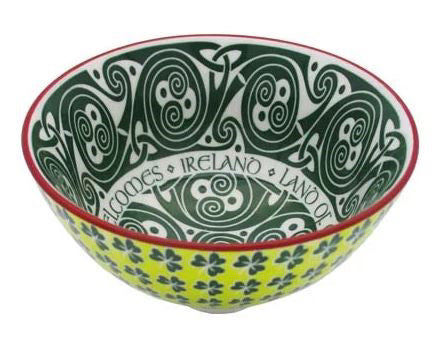 A colorful small bowl with a emerald green spiral knots on the inside, and yellow-green with small shamrocks on the outside. The rim of the bowl is red.