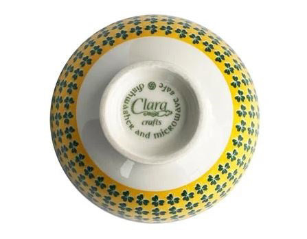 The bottom of the bowl is white and says Clara crafts: dishwasher and microwave safe. The sides of the bowl are yellow-green with tiny shamrocks.