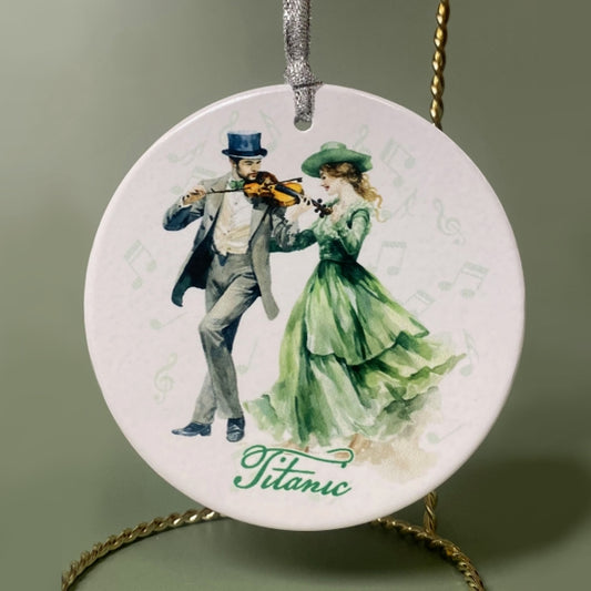 A round ceramic white ornament printed with an image of an Irish couple in formal attire dancing to a fiddle tune.