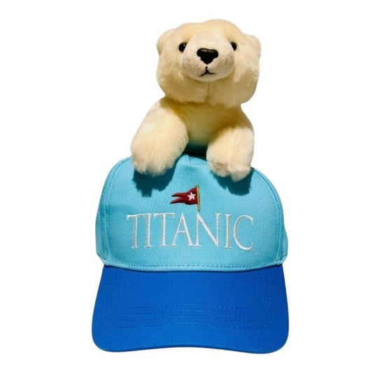 A view straight on of the youth Titanic baseball cap with embroidered logo and a plush polar bear on top.
