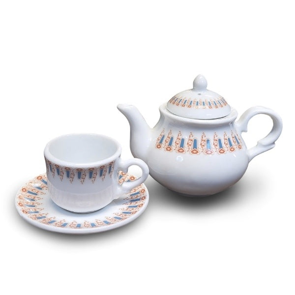 A miniature white teacup, saucer, and teapot with a light blue and brown swirling arches design around the rim. The cup is slightly smaller than a shot glass.
