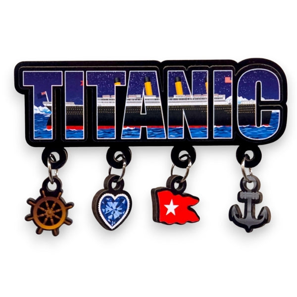A magnet of the word TITANIC in bold letters with four dangling charms hanging across its bottom - a ship's wheel, a blue heart, a red flag, and an anchor. An image of the ship can be seen within the shapes of the letters.