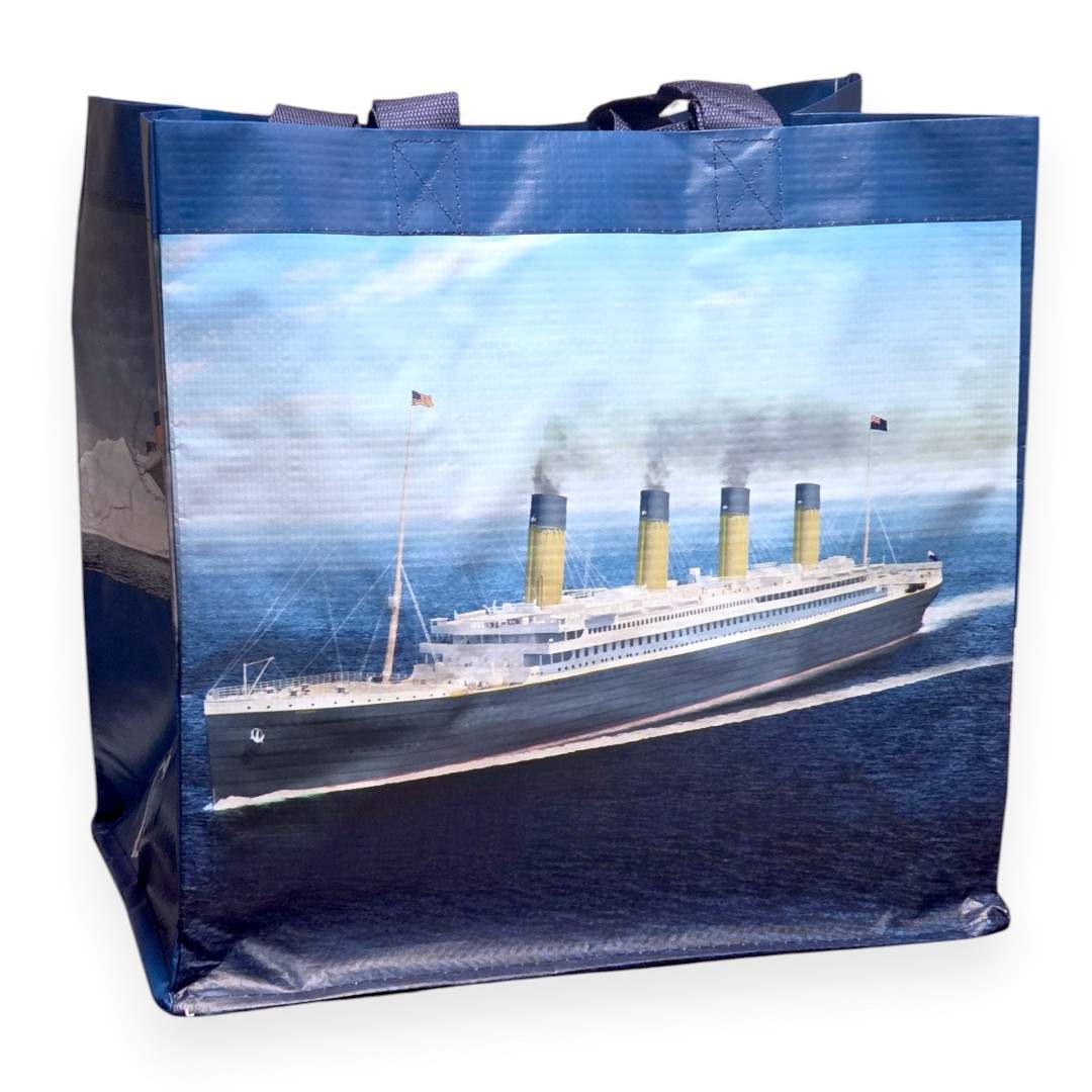 A large blue shopping tote bag with an illustration of Titanic sailing on a bright day under clear skies.