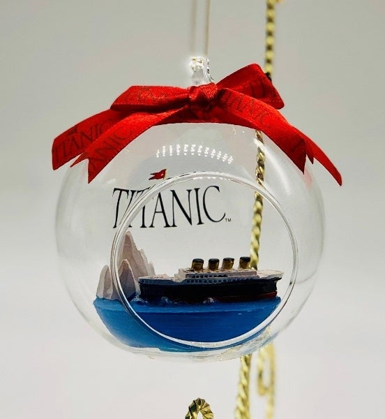A tiny sculpture of Titanic nears the iceberg inside this open glass ball ornament with a red bow on top.