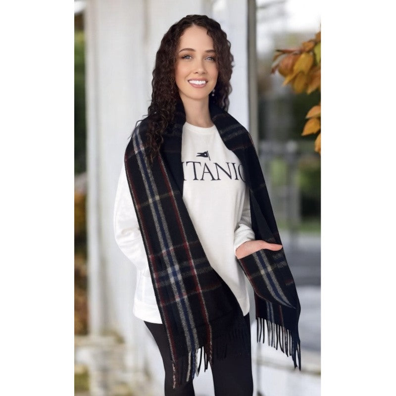 A young woman with curly brown hair models the primarily black Spirit of Titanic wool pocket scarf.