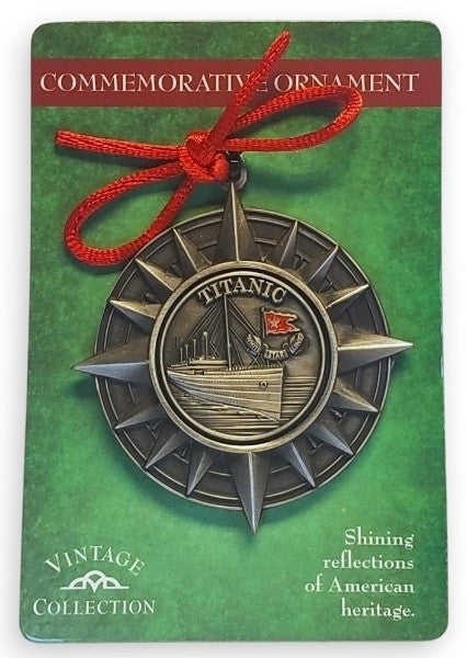 A star-like compass in gunmetal tones frames a pewter emblem of the Titanic at sea, topped off with a red string bow.