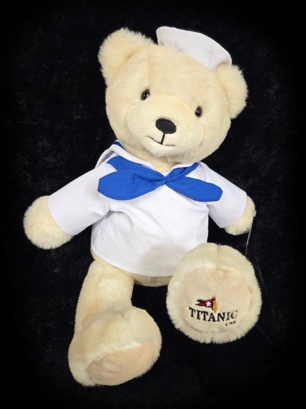 Polar bear plush wearing white sailor shirt with blue scarf.
