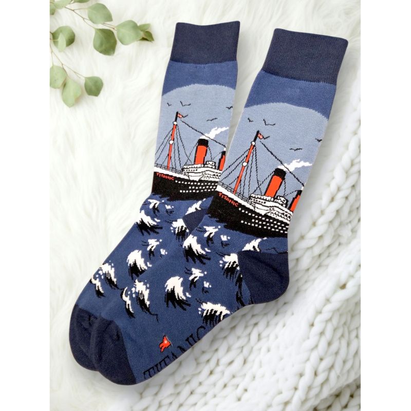 Titanic socks with several shades of blue. The ship is black and white with orange smokestacks and details. It is sailing across waves as birds fly in the distance overhead.