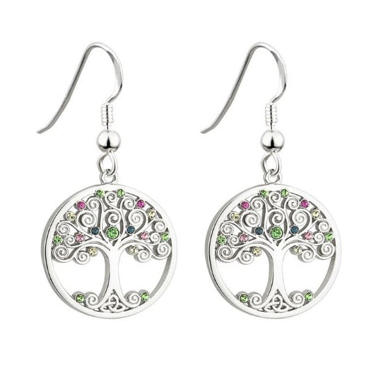 A pair of round, silver tone earrings of a tree with swirly branches decorated with multicolor glass crystals, and a trinity knot for roots.