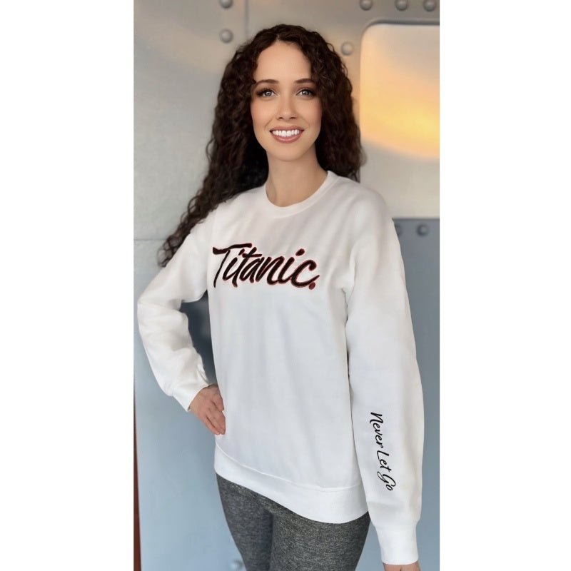 Woman with curly dark hair models a white sweatshirt that says Titanic in cursive on the chest and Never Let Go on one sleeve.