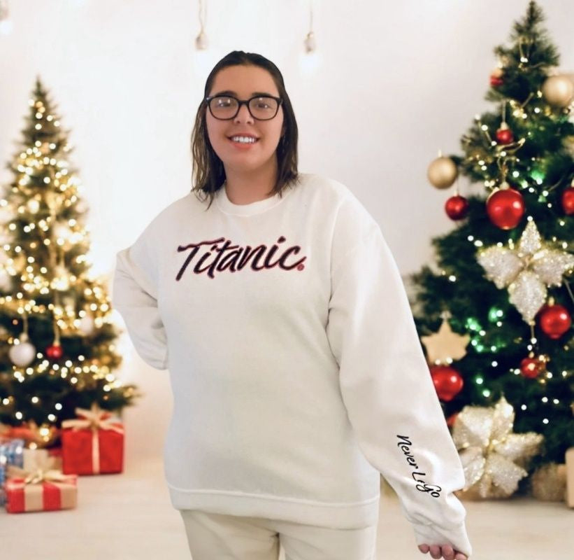 A young woman with glasses models the same white sweatshirt in a larger size with a festive background.