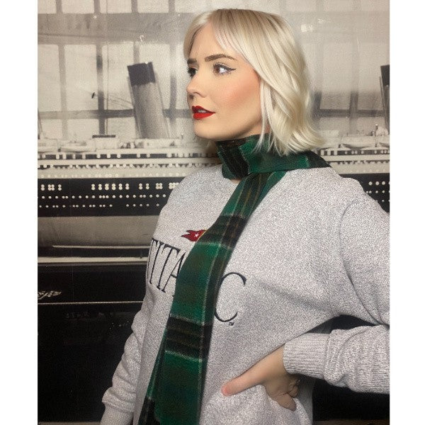 A woman looks to the side while wearing a green tartan wool scarf.