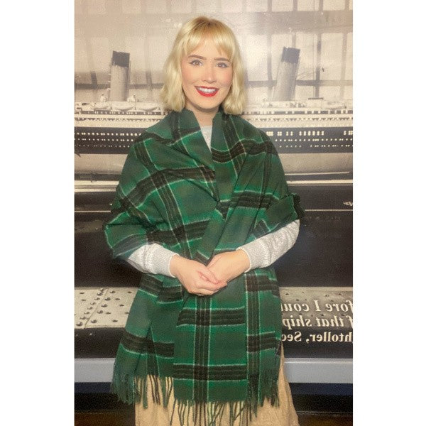 A cheerful woman is wrapped up warmly in a green tartan wool stole.