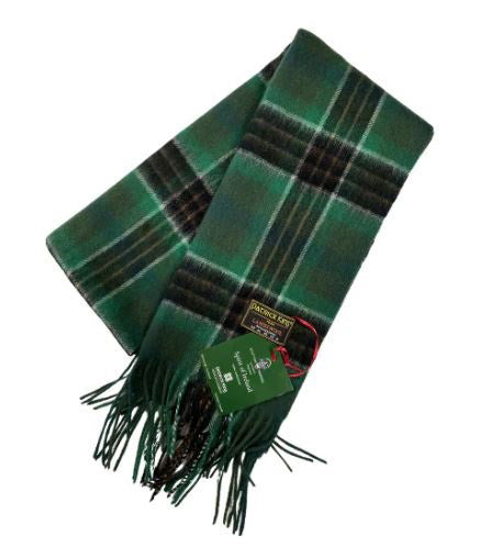 A green tartan scarf with fringe lies folded neatly.