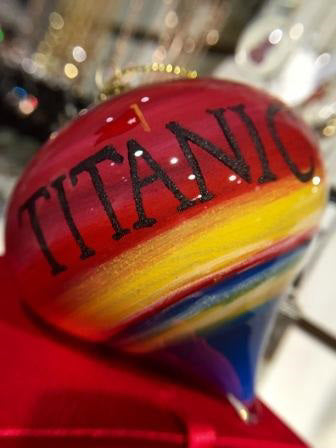 The Titanic's name is printed in large black lettering across the sunset sky of red and yellow. The ornament is glossy smooth because the paint is on the inside.