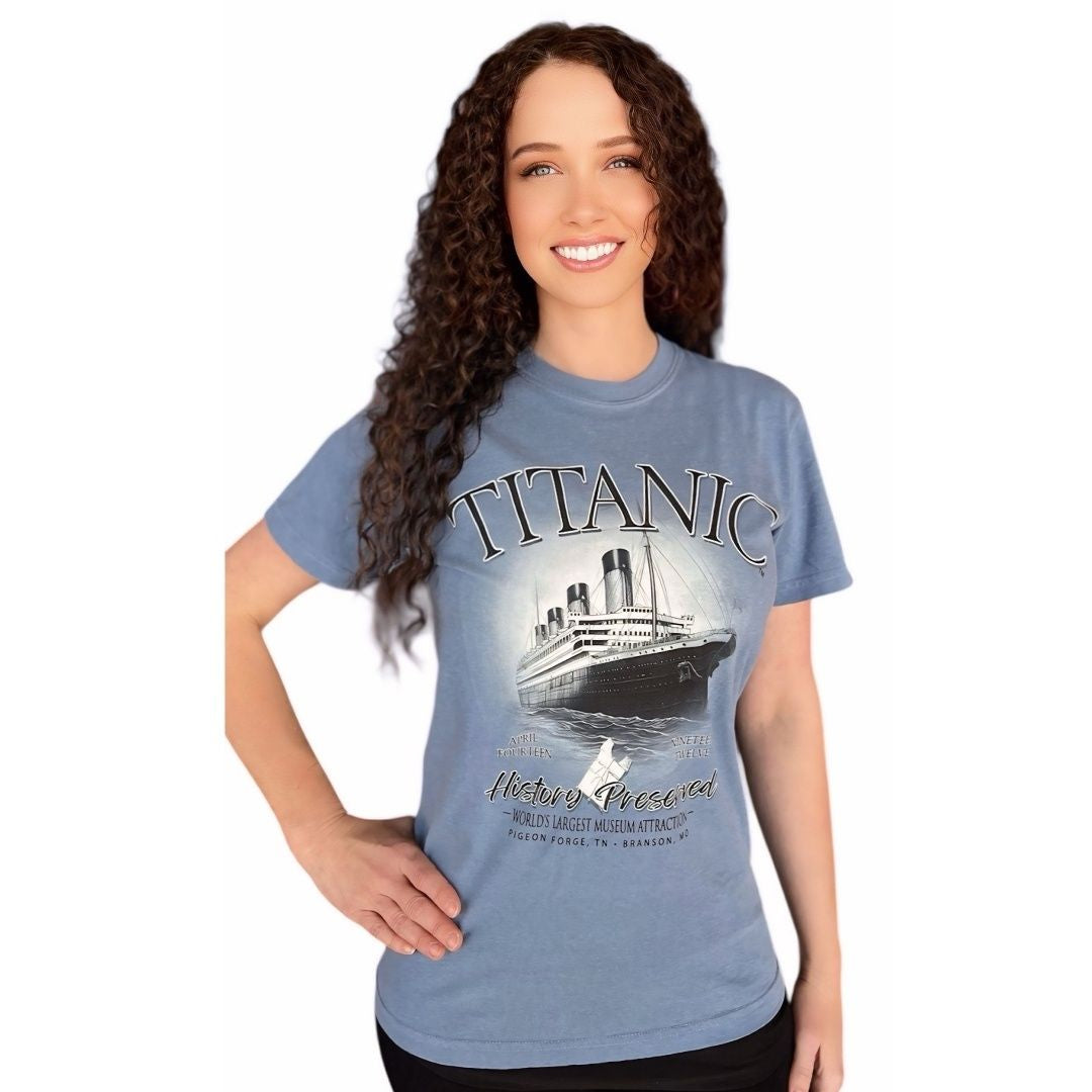 A young woman wearing a muted denim blue t-shirt featuring the Titanic and a 1912 life jacket.