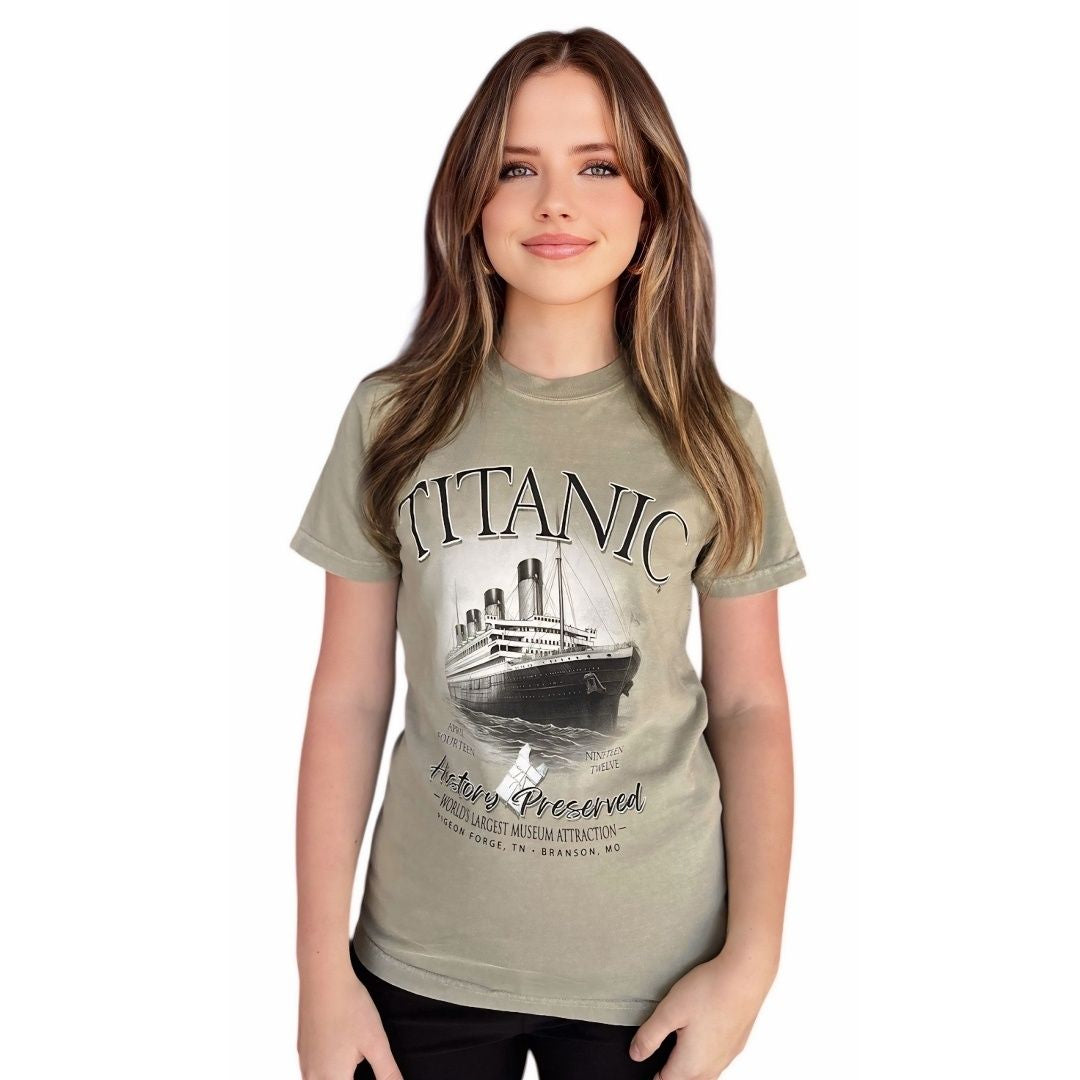 A young woman wearing a muted sage green t-shirt featuring the Titanic and a 1912 life jacket.