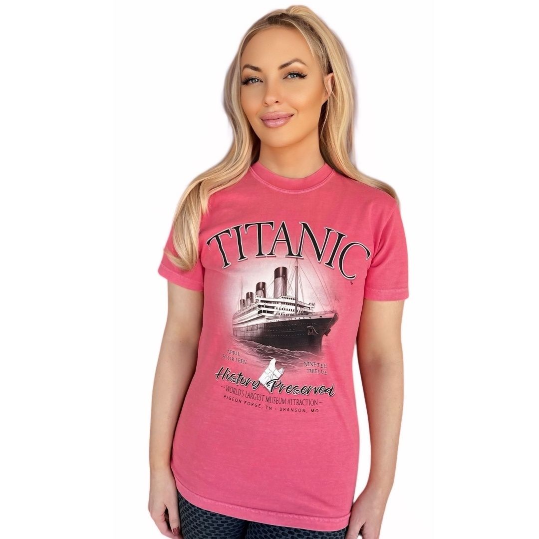 A young woman wearing a watermelon pink t-shirt featuring the Titanic and a 1912 life jacket.