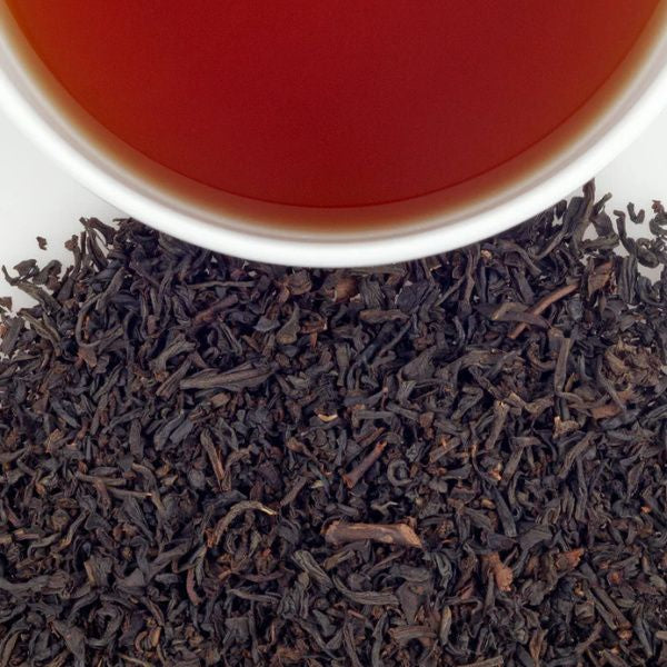 A closeup of the tea unpackaged showing a mix of dark reddish dried tea plants. The tea will arrive in sachets in the tin. It makes a reddish tea.