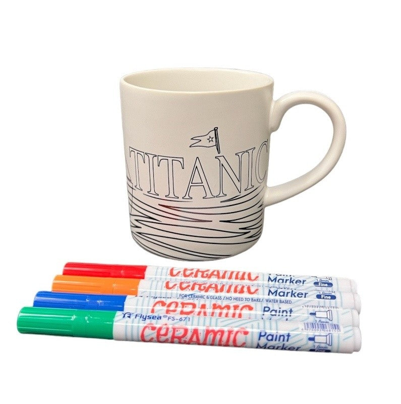 A white mug with uncolored Titanic illustrations and the four specialty markers used to decorate it.