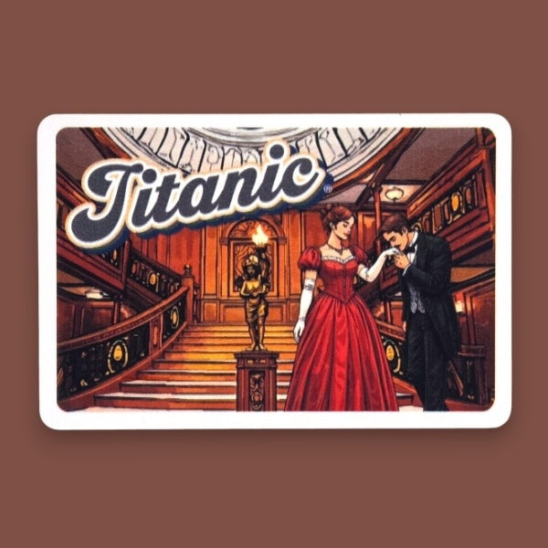 A gentleman kisses a lady's hand on the grand staircase, printed on a rectangular magnet with a white border and the word "Titanic" written in bold italic text.